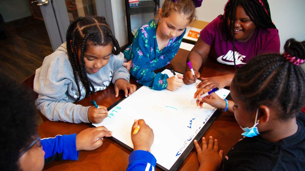 Rita-June-kids-writing-names-on-whiteboard